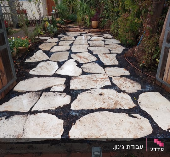 אבנים גדולות מונחות בשביל בגינה עם צמחים מסביב